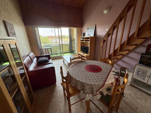 - un salon avec une table, des chaises et des escaliers dans l'établissement Studio Mezzanine Confortable Aux Sables-d'Olonne - Proche Plage et Marché Arago - FR-1-92-835, à Les Sables-dʼOlonne