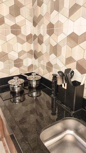 a kitchen counter with two pans on top of it at Studio 61- No Coração de Curvelo in Curvelo