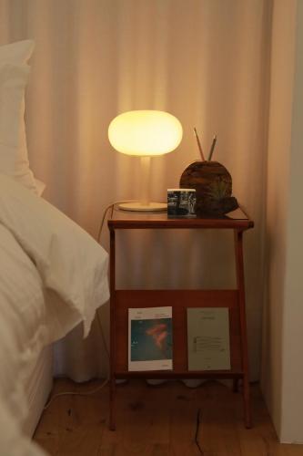 a table with a lamp on it next to a bed at Stay Hosa in Suwon