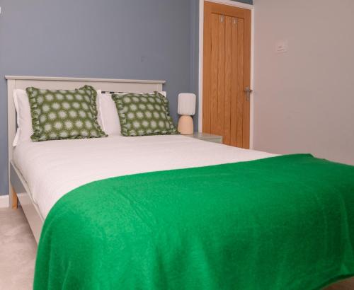 a bedroom with a green blanket on a bed at The Whitehouse M6, Junction 10 With Parking in Walsall