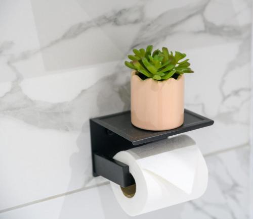 a plant in a pot sitting on a toilet paper holder at The Whitehouse M6, Junction 10 With Parking in Walsall