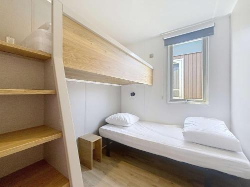 Cette petite chambre comprend des lits superposés et une fenêtre. dans l'établissement Mobil-Home Confort 4 Pers, à 200m Plage, Terrasse, Piscine Chauffée, Parking, Wi-Fi Gratuit - FR-1-361A-83, à Jullouville
