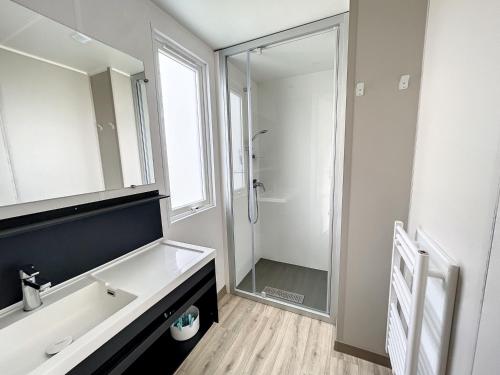 une salle de bain blanche avec un lavabo et une douche dans l'établissement Mobil-home Grand Confort proche plage avec piscine chauffée, fitness et parking, Jullouville - FR-1-361A-17, à Jullouville