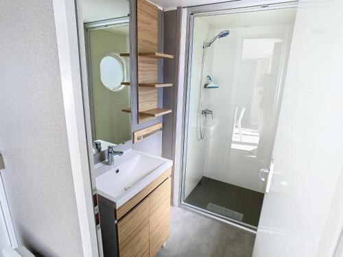 une salle de bain avec un lavabo et une douche avec un miroir dans l'établissement Mobil-Home Grand Confort: 6 Pers, 3 Ch, Piscine Chauffée, Proche Plage et Commerces - FR-1-361A-33, à Jullouville