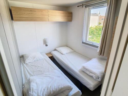 deux lits dans une petite pièce avec une fenêtre dans l'établissement Mobil-Home Grand Confort: 6 Pers, 3 Ch, Piscine Chauffée, Proche Plage et Commerces - FR-1-361A-33, à Jullouville