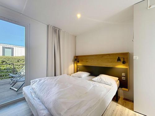 une chambre avec un grand lit et un balcon dans l'établissement Mobil-home Grand Confort: 2 ch, piscine, plage à 200m, parking, wifi - FR-1-361A-96, à Jullouville