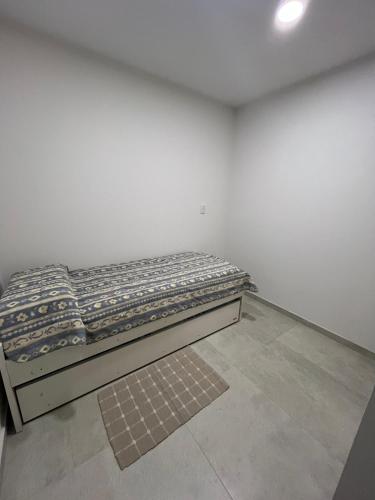a bed in a room with a white wall at Andes Nomad Mendoza in Godoy Cruz