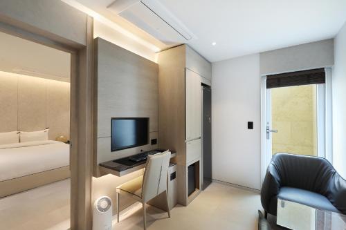a bedroom with a bed and a desk with a television at Hound Hotel Asan Terminal in Asan