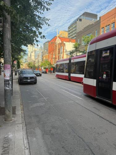 a red and white train on a city street with cars at King-Queen Walk-in Residence - Walk to CN TOWER,SUBWAY,CONCERTS,PUBS,PARKING in Toronto