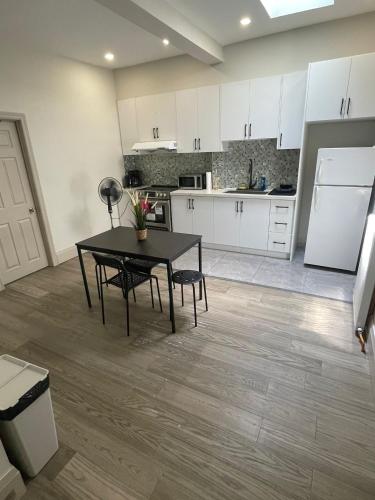 a kitchen with white cabinets and a table and a refrigerator at King-Queen Walk-in Residence - Walk to CN TOWER,SUBWAY,CONCERTS,PUBS,PARKING in Toronto