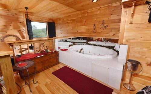 een grote badkamer met een bad in een houten hut bij Mountain Romance in Sevierville