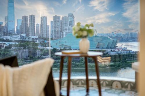 a vase of flowers on a table in front of a window at Baihong Riverview Apartment-Hongya Cave in Chongqing