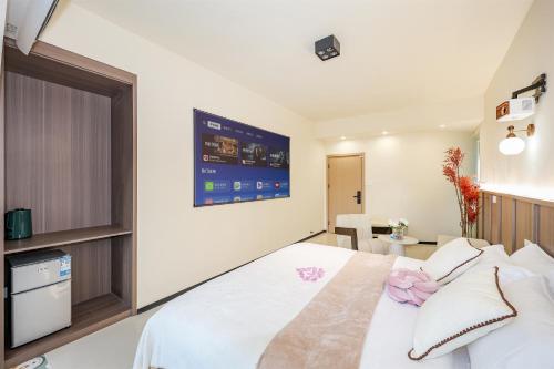 a bedroom with a white bed and a tv on the wall at Baihong Riverview Apartment-Hongya Cave in Chongqing