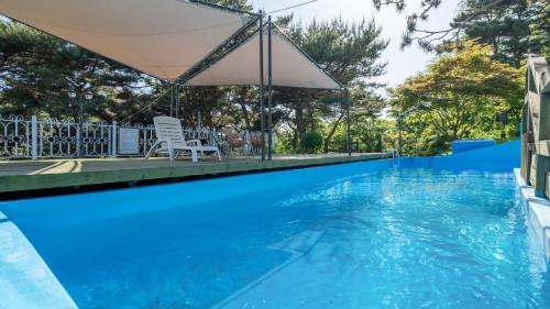 una piscina con una silla y una sombrilla en Seokmodo supsokbadapunggyeong pension, en Incheon