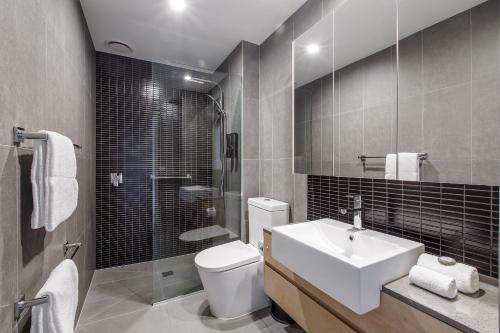 a bathroom with a toilet and a sink and a shower at Artel Apartments Brunswick in Melbourne
