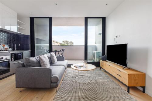 a living room with a couch and a tv at Artel Apartments Brunswick in Melbourne