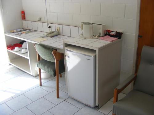 eine Küche mit einer Theke mit einem Kühlschrank und einem Tisch in der Unterkunft Central Motel in Rarotonga
