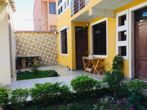 a yellow house with a table in front of it at Casa Departamento Jardín en Cochabamba in Cochabamba