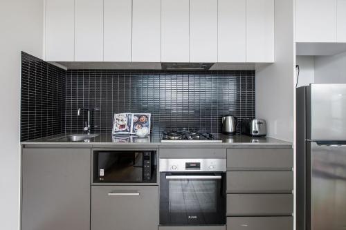 a kitchen with a sink and a stove top oven at Artel Apartments Brunswick in Melbourne