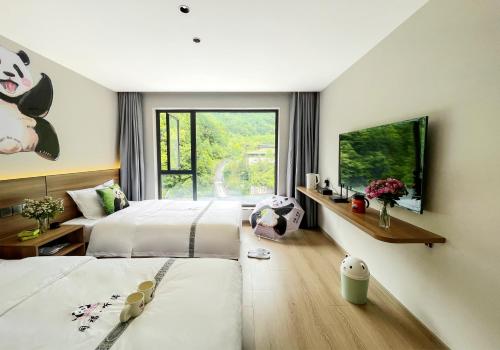 una camera da letto con due letti e una grande finestra di Wolong Tongfu Tingtao B&B, China Great Beauty Bear Store a Wolongguan