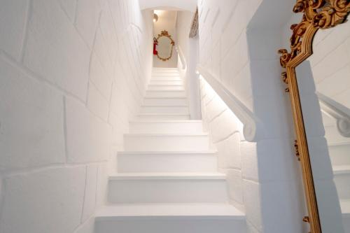 a white staircase with a mirror next to it at Luxury Palazzo Principessa - Elegance and History in Center in Monopoli