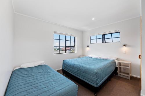 two beds in a room with two windows at Knightsbridge Court Motor Lodge in Blenheim