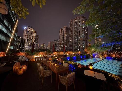 a patio with tables and chairs and a pool at night at Kempinski The One Suites Hotel Shanghai Downtown in Shanghai