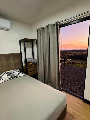 a bedroom with a bed and a large window at Hospedagem Morro do Buda Container in Planalto