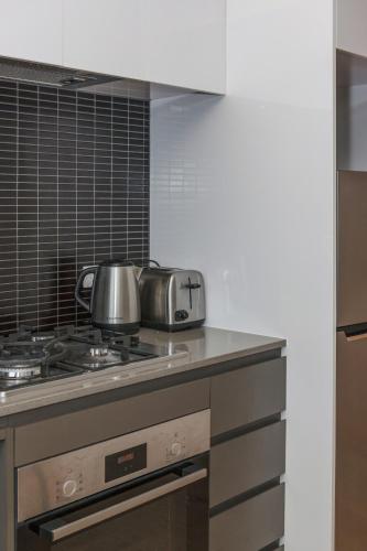 a kitchen with a stove with a tea pot on it at Artel Apartments Brunswick in Melbourne