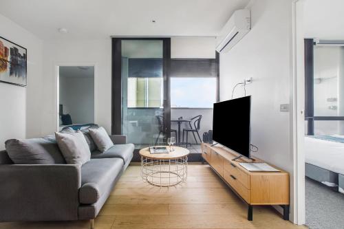 a living room with a couch and a tv at Artel Apartments Brunswick in Melbourne