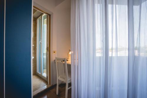 a room with a crib and a window with curtains at Hotel Raffaello in Bellaria-Igea Marina