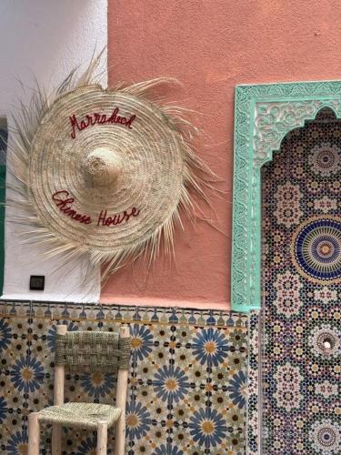 a straw hat and a chair next to a wall at 里院 Daoudiate courtyard in Marrakech