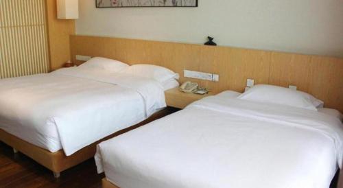 two beds in a hotel room with white sheets at Xian Elegant Oriental Hotel in Xi'an
