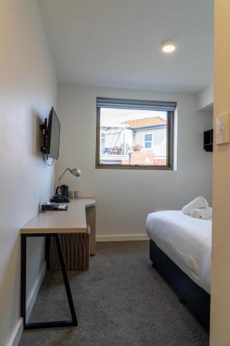 a bedroom with a bed and a desk and a window at Cosmopolitan Hotel and Apartments in Melbourne