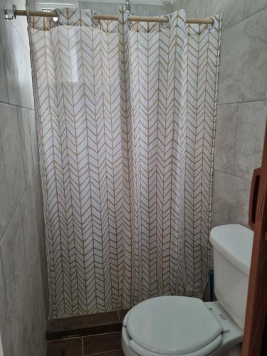 a bathroom with a toilet and a shower curtain at La casa del mar in Manzanillo