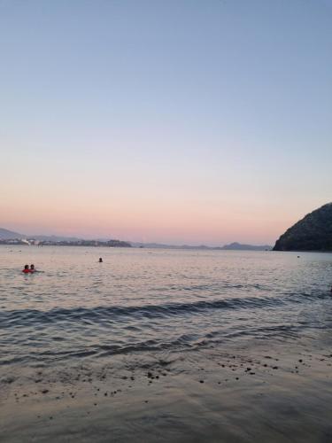 a beach with people in the water at sunset at La casa del mar in Manzanillo