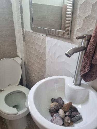 a bathroom with a toilet and a sink with rocks in it at La casa del mar in Manzanillo