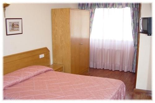 a bedroom with a bed and a dresser at Hostal Arlanzón in Burgos