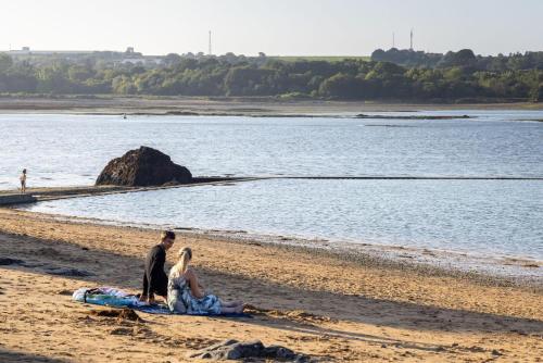 a man and woman sitting on a surfboard on the beach at Ty yar in Plourivo