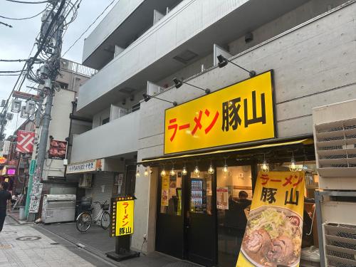 a store with a yellow sign on the side of a building at West Shinjuku Nakano Family Inn in Tokyo