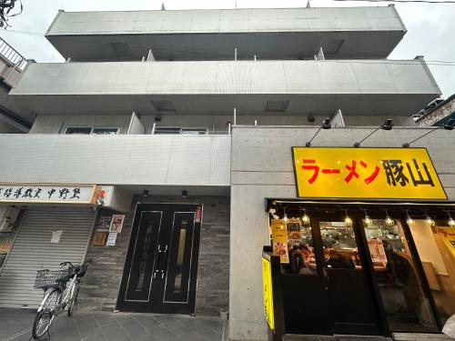 a store with a yellow sign in front of a building at West Shinjuku Nakano Family Inn in Tokyo