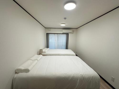 a bedroom with two beds and a window at West Shinjuku Nakano Family Inn in Tokyo