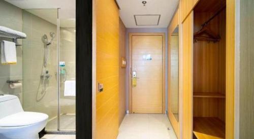 a bathroom with a shower and a toilet and a glass door at City Comfort Inn Lichuan Railway Station Tenglong Cave in Enshi