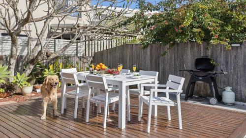 a dog standing next to a white table and chairs at Pippi House - A Quintessential Beach House - Holiday Yamba in Yamba