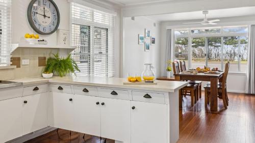 a kitchen with a clock on the wall and a table at Pippi House - A Quintessential Beach House - Holiday Yamba in Yamba