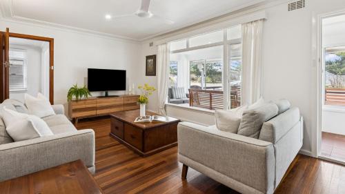 a living room with two chairs and a flat screen tv at Pippi House - A Quintessential Beach House - Holiday Yamba in Yamba