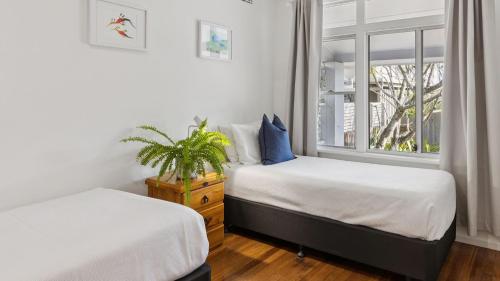 two beds in a room with a window at Pippi House - A Quintessential Beach House - Holiday Yamba in Yamba