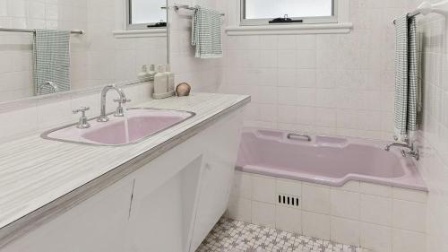 a bathroom with a pink sink and a mirror at Pippi House - A Quintessential Beach House - Holiday Yamba in Yamba