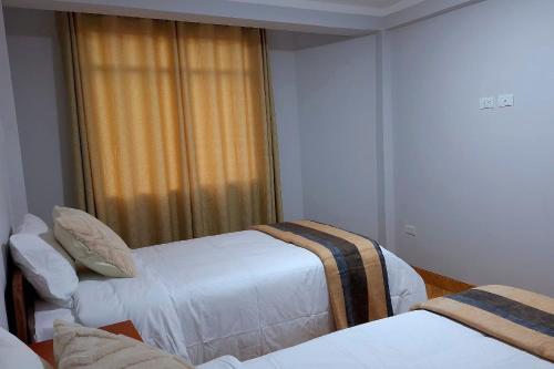 a hotel room with three beds and a window at Misha House in Huaraz