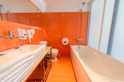a bathroom with a tub and a sink and a toilet at Inn OZZ in Karagandy